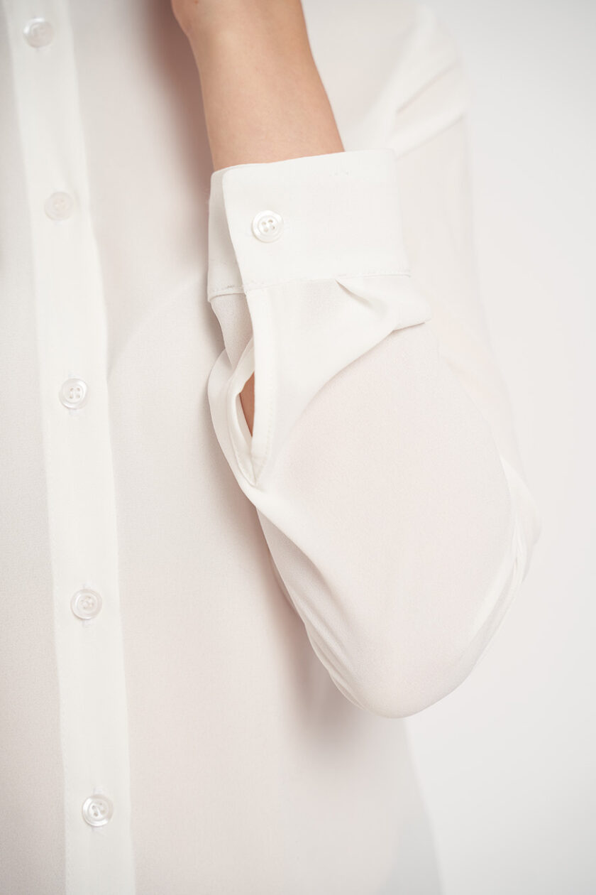 Cămașă albă cu un aspect modern și guler tunică. Fabricată dintr-o țesătură moale, puțin transparentă.
